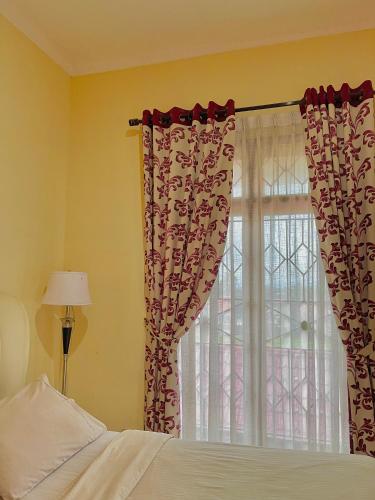 a bedroom with a bed and a window with curtains at Sapo Karo Rest House in Berastagi
