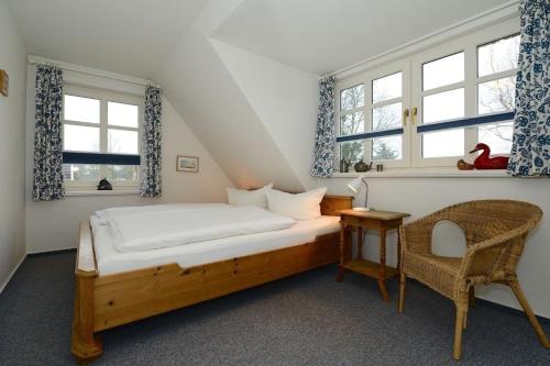 a bedroom with a bed and a chair and windows at Haus Bornholm Whg 23 in Nieblum