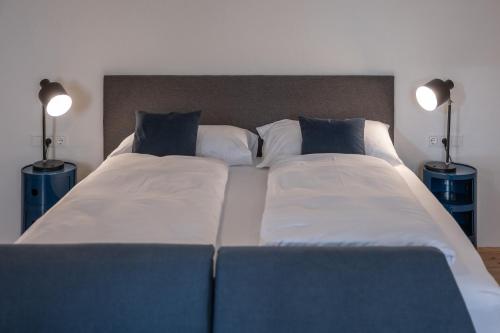 a large bed with two pillows and two lamps at Tschardakenhof Appartements in Lutzmannsburg