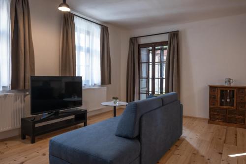 a living room with a blue couch and a television at Tschardakenhof Appartements in Lutzmannsburg
