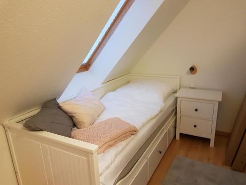 a white bed in a attic with a window at Haus Sonnenwind in Zingst