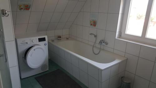 a bathroom with a tub sink and a washing machine at Haus Sonnenwind in Zingst