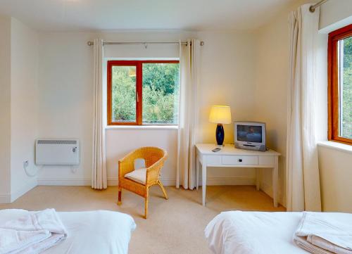 een slaapkamer met een bureau, een stoel en een televisie bij Lakeside Holiday Homes - Type B in Killaloe