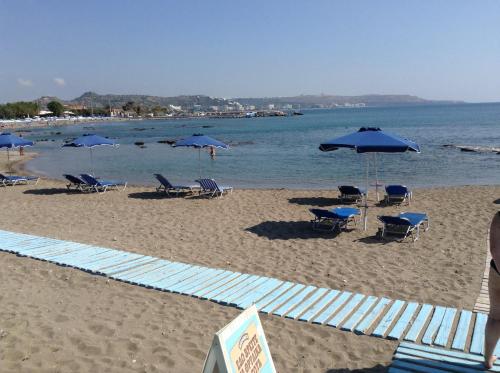 a beach with chairs and umbrellas and the ocean at Elpida Beach Studios in Faliraki