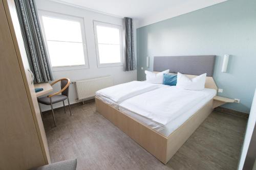 a bedroom with a large white bed and a chair at Rosen-Hotel in Sangerhausen