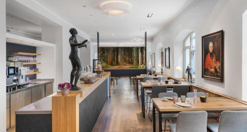 um restaurante com mesas e uma estátua de uma mulher em Alpen Hotel München em Munique