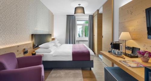 a hotel room with a bed and a tv at Alpen Hotel München in Munich