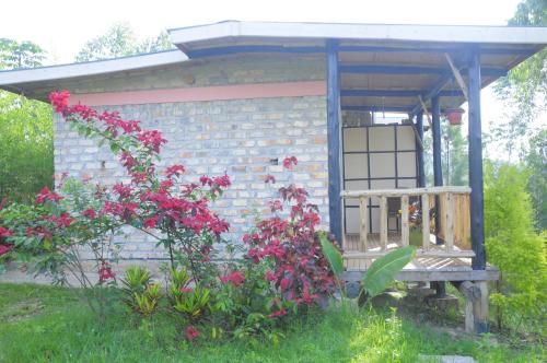 a small brick house with a porch and flowers at Muga Eco Village in Ntungamo
