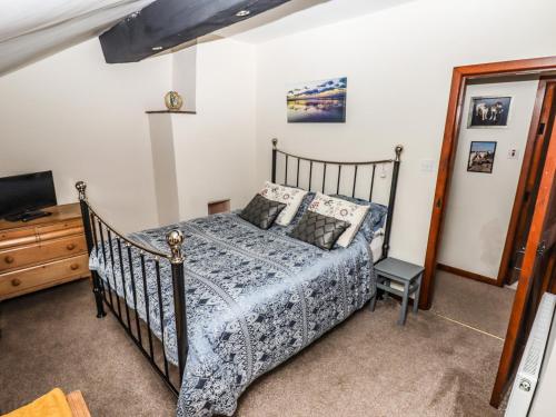 a bedroom with a bed and a dresser and a tv at Bendigedig in Blackburn