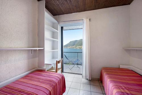 two beds in a room with a view of the ocean at Residence La Cava Trilocale 1d in Pognana Lario