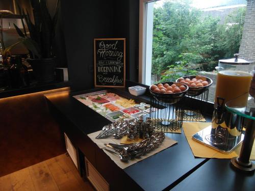 a counter with a buffet of food and a drink at Hotel Sanders de Paauw in Sluis