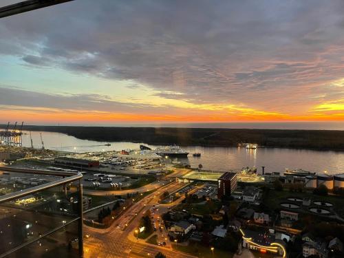 a sunset over a city with a harbor and water at 34 floor at the top of the Baltic in Klaipėda