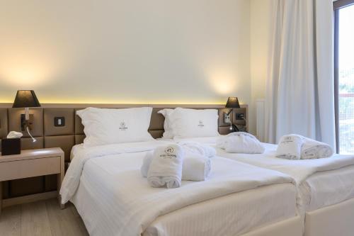 two beds in a hotel room with towels on them at Ayia Marina Suites in Ouranoupoli