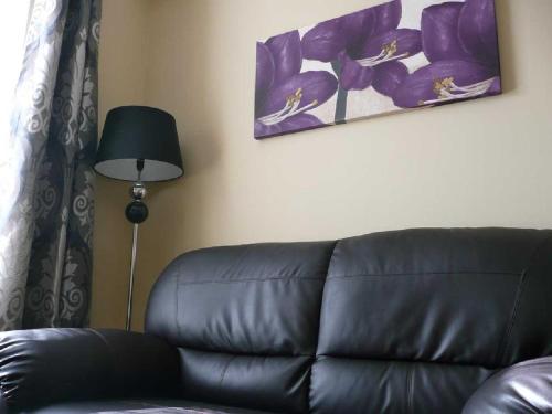 a black leather couch in a living room with a lamp at The Bahamas in Torquay