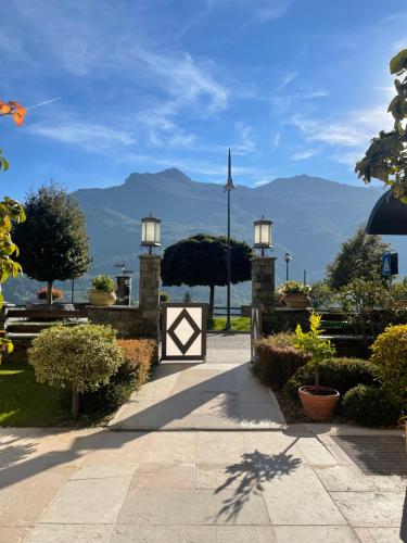 a pathway with a gate and mountains in the background at Paradise Hotel & Wellness in Saint Vincent