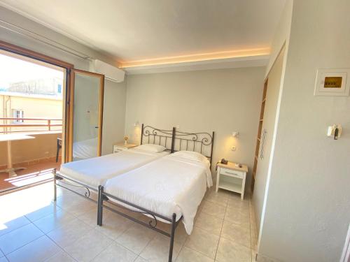 a bedroom with a bed and a large window at Louvre Hotel in Gouvia