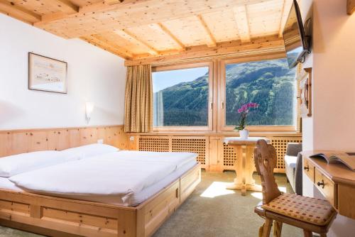 um quarto com uma cama, uma secretária e uma janela em Chesa Languard em St. Moritz