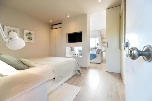 a white bedroom with a bed and a tv at Gava Ocean View in Gavà