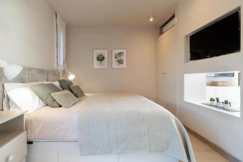 a white bedroom with a bed and a flat screen tv at Gava Ocean View in Gavà