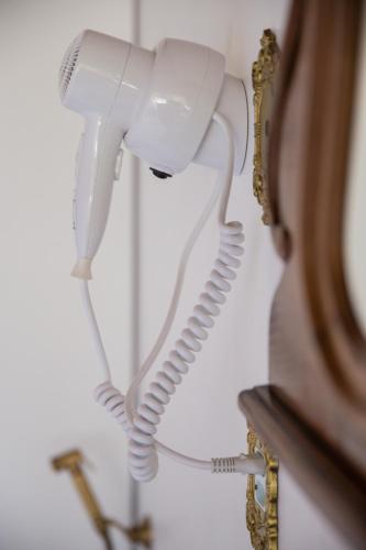 a white phone hanging on a wall next to a mirror at Pousada Dona Bendita in Monte Verde