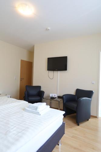a room with two chairs and a bed and a flat screen tv at Hotel Restaurant Zagreb in Cologne