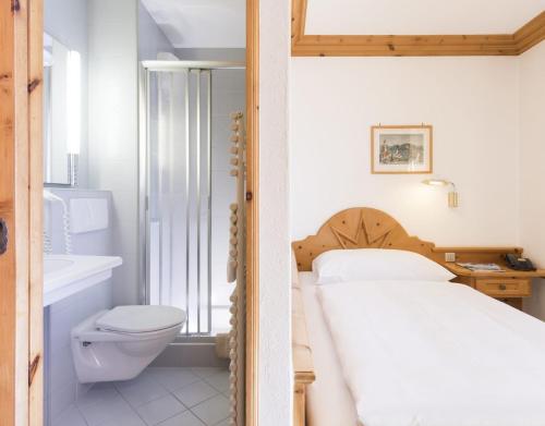 uma casa de banho com uma cama, um WC e um lavatório. em Chesa Languard em St. Moritz