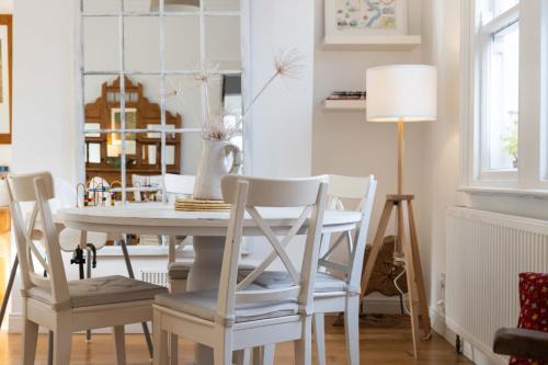 a dining room with a white table and chairs at Stylish 2BR Cottage Garden & Parking 5 mins to Titanic in Belfast