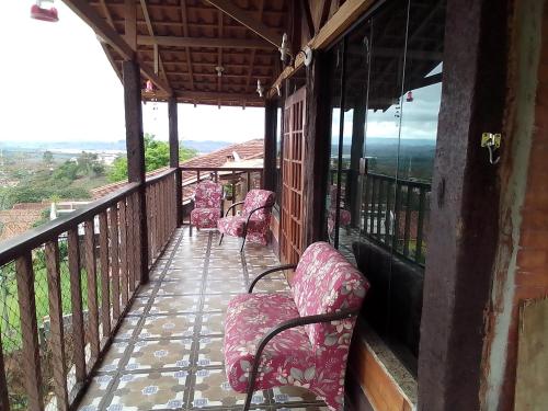 a balcony with pink chairs on a building at Casa de Tijolinho Penedo-RJ in Penedo