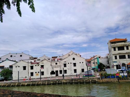 a row of white buildings next to a body of water at Alimama Guesthouse Melaka with Balcony in Melaka
