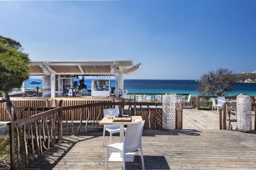 a wooden deck with a table and chairs on the beach at Smart Suite & Apartments in Santa Teresa Gallura