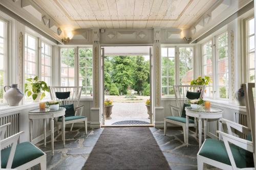 a room with windows and tables and chairs at Ronnums Herrgård in Vargön
