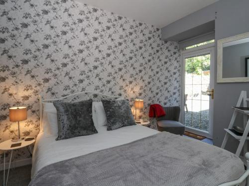 a bedroom with a bed and a wall with floral wallpaper at The Coorie Cove in Helensburgh
