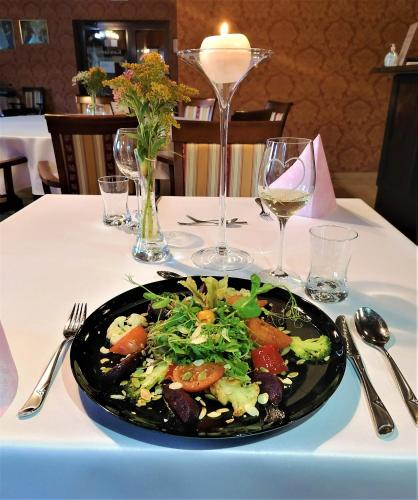 a plate of salad on a table with wine glasses at Dwór Maria Antonina in Strzyżów