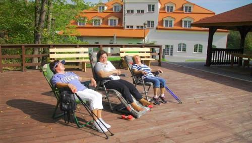 three people sitting in chairs on a deck at Dwór Maria Antonina in Strzyżów