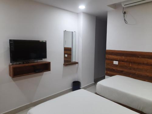 a room with two beds and a flat screen tv at Hotel Prime Jubilee in Hyderabad