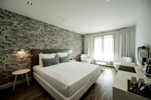 サン・テギュルフにあるオテル ル カタローニャの白い大型ベッドと壁画が備わるベッドルーム1室が備わります。