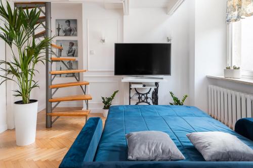 a living room with a blue bed and a flat screen tv at Apartament Królewska by Your Freedom in Warsaw