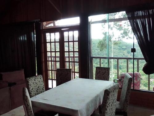 a dining room with a table and chairs and windows at Casa de Tijolinho Penedo-RJ in Penedo