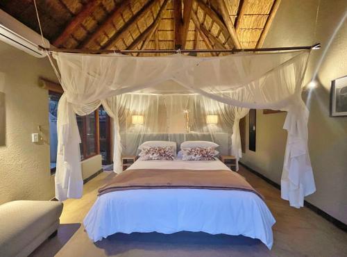 sypialnia z dużym łóżkiem z baldachimem w obiekcie 10 Raptors Lodge w mieście Hoedspruit