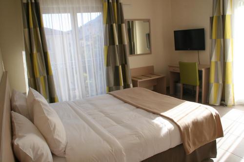 a bedroom with a bed and a desk and a television at The Originals Boutique, Hotel l'Occitan, Aubagne in La Destrousse