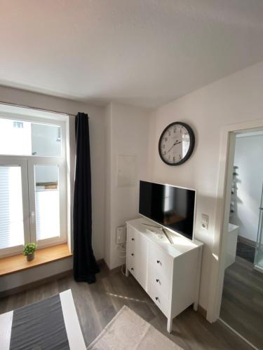a living room with a tv and a clock on the wall at FeWo Jade in Wilhelmshaven