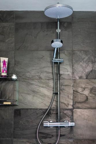 a shower in a bathroom with a stone wall at The Costrel in Tenbury