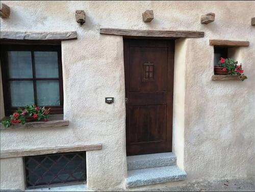a building with a wooden door and two windows at B&B e Home Restaurant S'ispera Monolocale uso esclusivo in Fonni