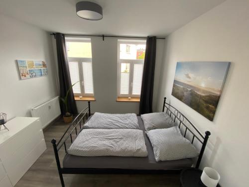 a bedroom with a bed and two windows at FeWo Jade in Wilhelmshaven