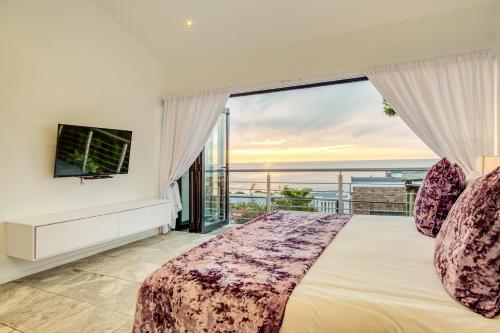 a bedroom with a bed and a large window at Sunset Views in Cape Town
