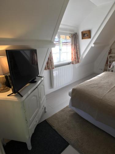 a bedroom with a bed and a flat screen tv at La Romance et la Romanesque in Berville-sur-Mer