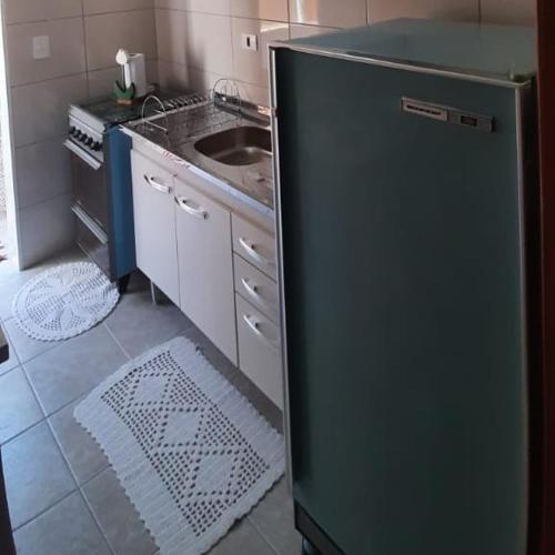 a kitchen with a refrigerator and a sink at Apto Tranquilo e Aconchegante no Centro de Águas de Lindoia in Águas de Lindóia