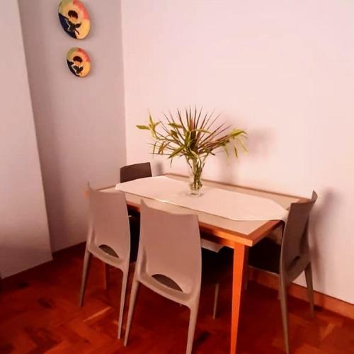 a dining room table with chairs and a vase on it at Apto Tranquilo e Aconchegante no Centro de Águas de Lindoia in Águas de Lindóia