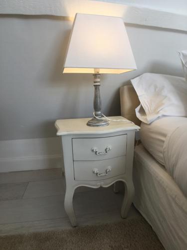 a lamp on a night stand next to a bed at La Romance et la Romanesque in Berville-sur-Mer