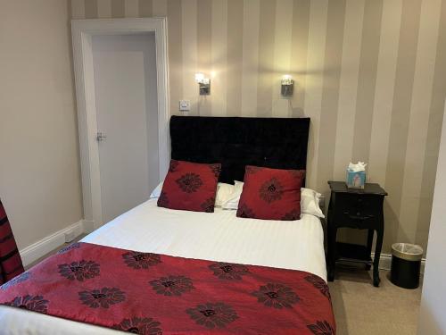 a bedroom with a large bed with red pillows at The Original Rosslyn Inn in Roslin